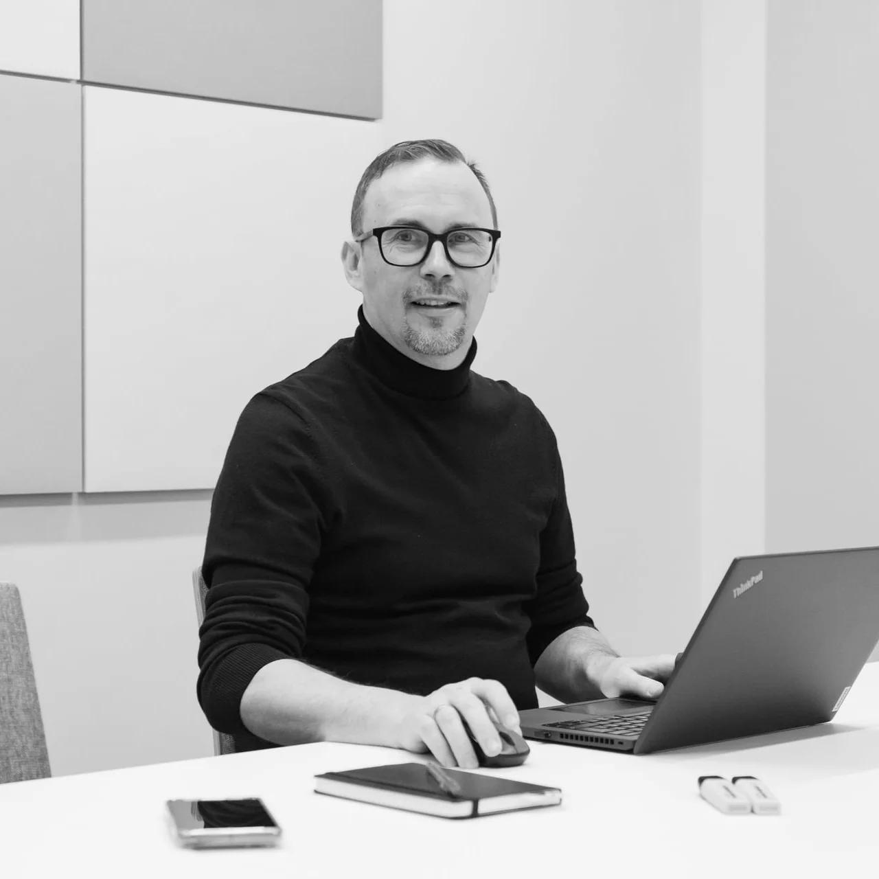 Timo istuu tietokoneen ääressä ja hymyilee kameralle.