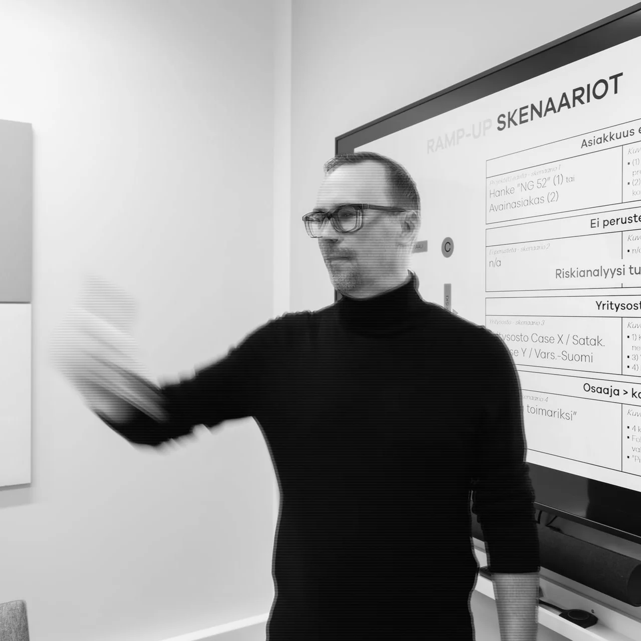 Timo seisoo neuvotteluhuoneen edessä ja kertoo skenaarioista.